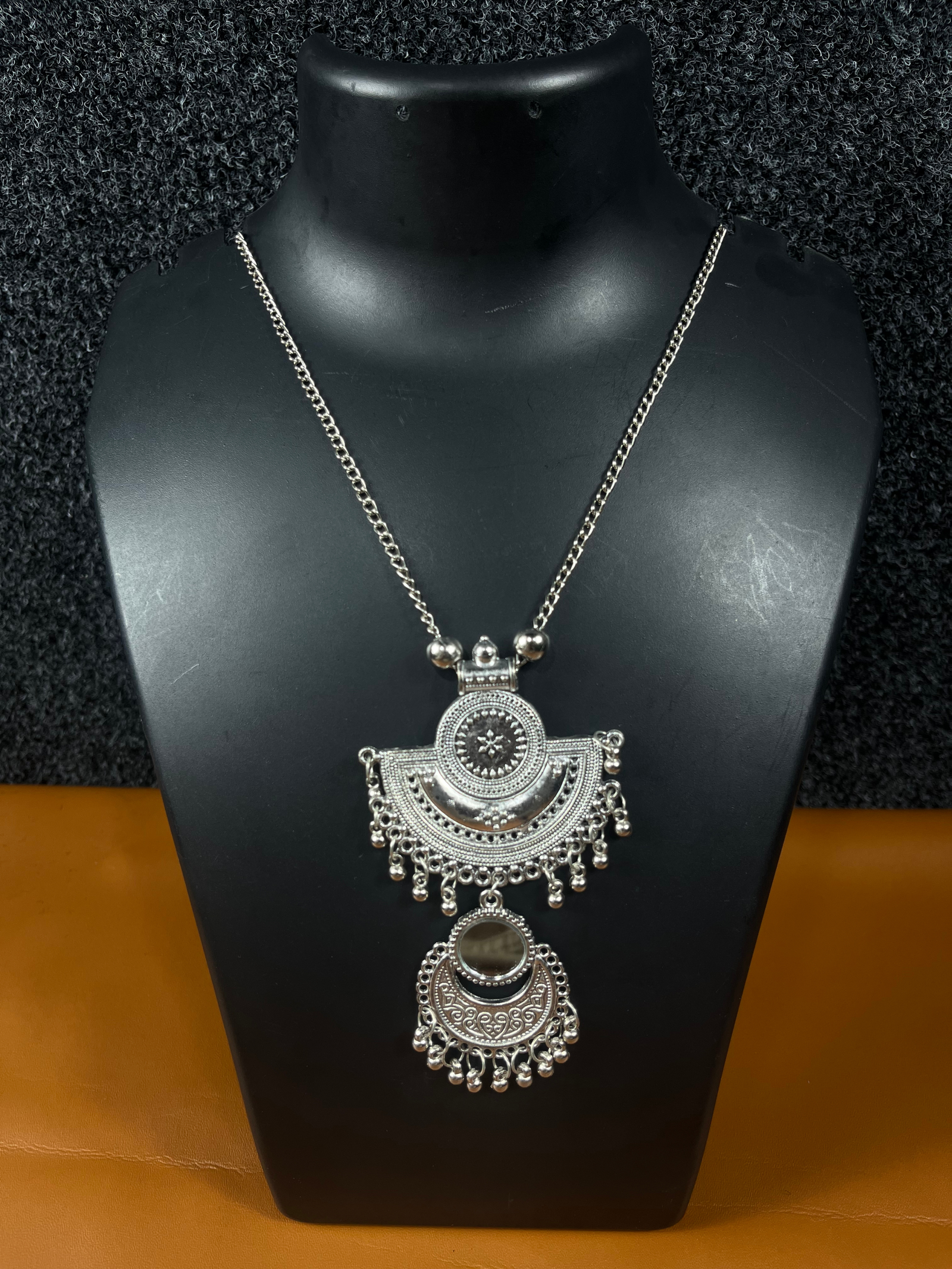 Oxidized silver double pendant necklace with intricate tribal design, featuring a half-moon and circular pendant, displayed on a black mannequin.