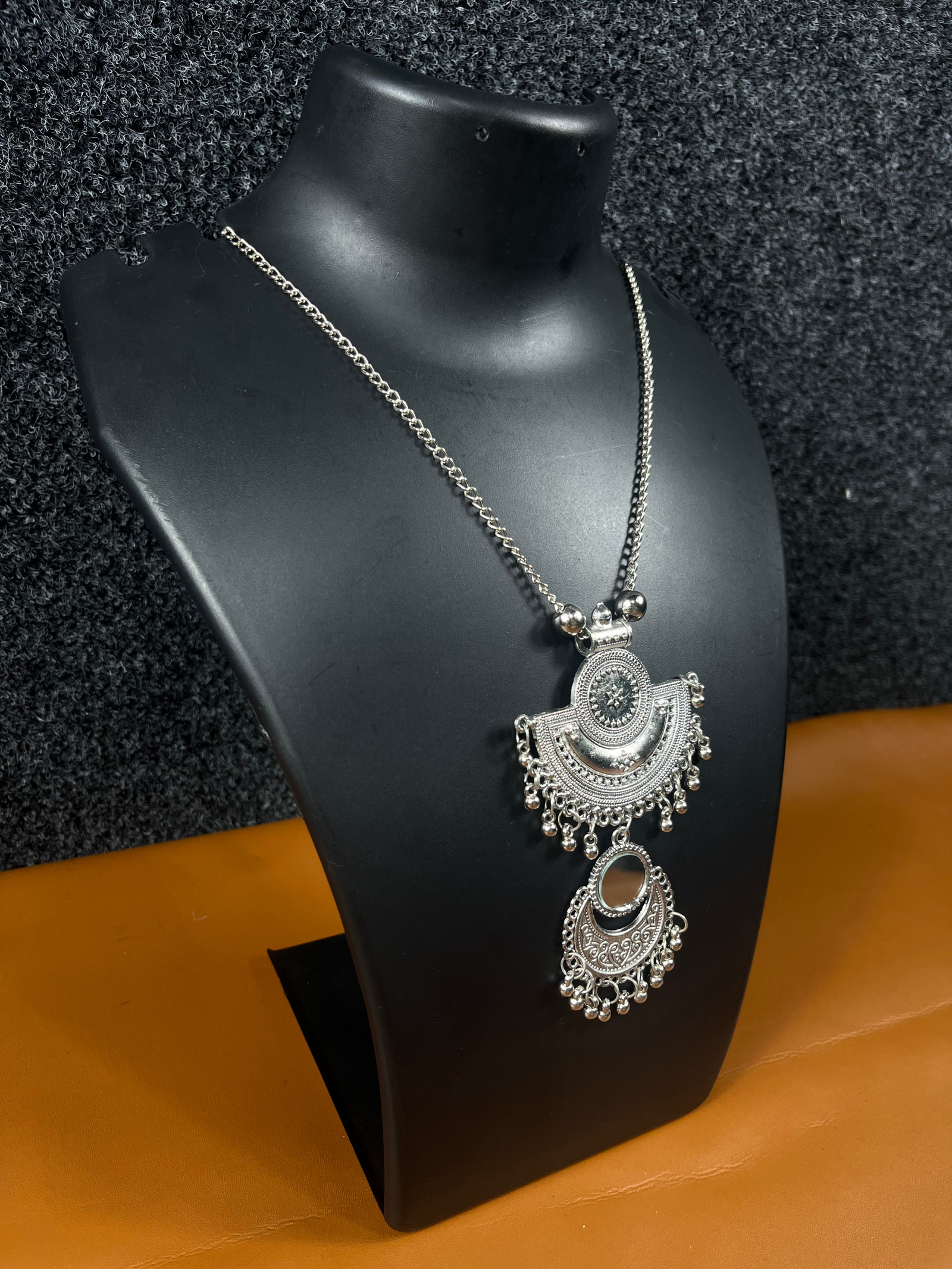 Oxidized silver double pendant necklace with intricate tribal design, featuring a half-moon and circular pendant, displayed on a black mannequin.